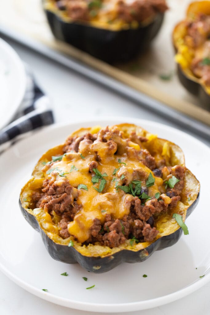 Final product of taco stuffed acorn squash on a white plate and garnished with cilantro.