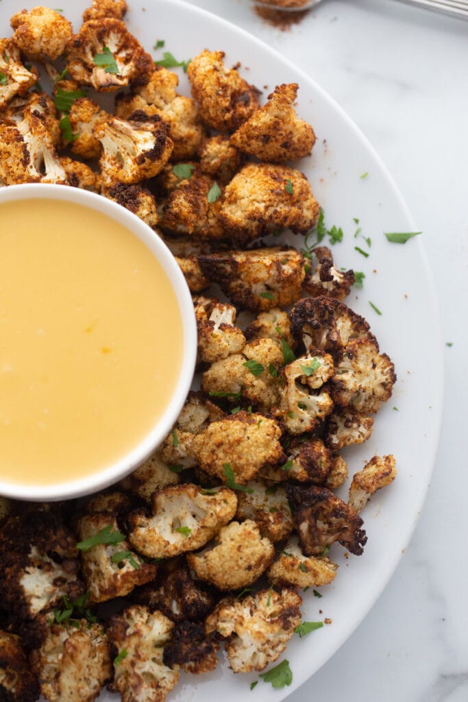 Overhead image: seasoned cauliflower with homemade cheese sauce on a platter