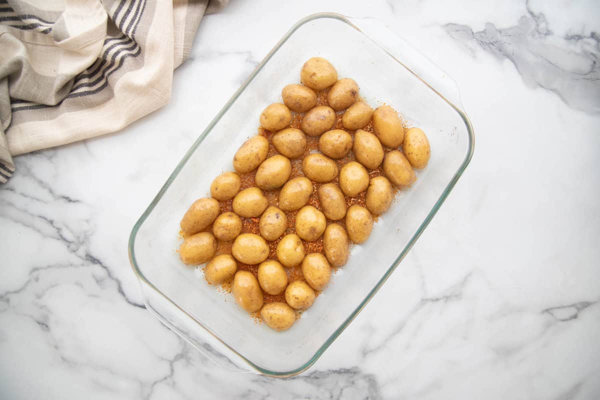 Baby potatoes cut side down in a glass pan.