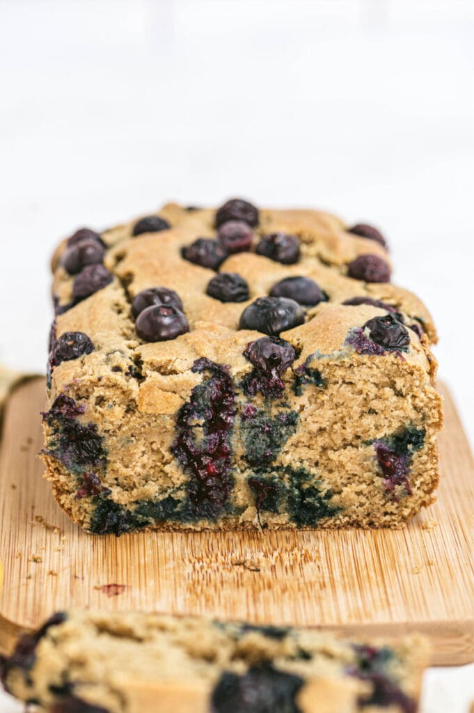 Closeup of lemon blueberry loaf on a cutting board with one slice removed from the bread