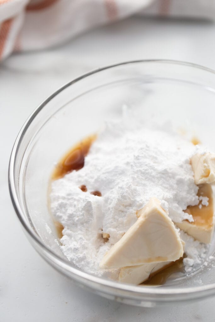 Ingredients for lightened up cream cheese frosting, in a glass mixing bowl