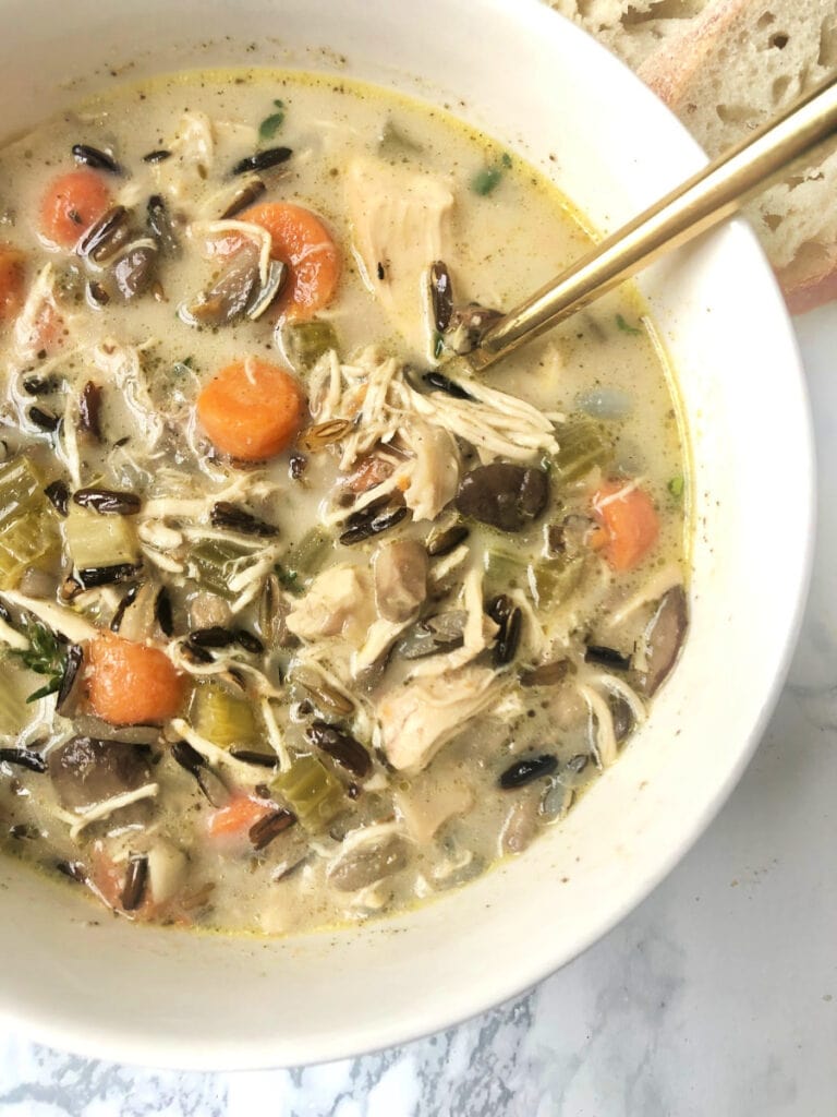 Close up photo of Instant Pot Chicken and Wild Rice Soup in a white bowl, ready to eat. 