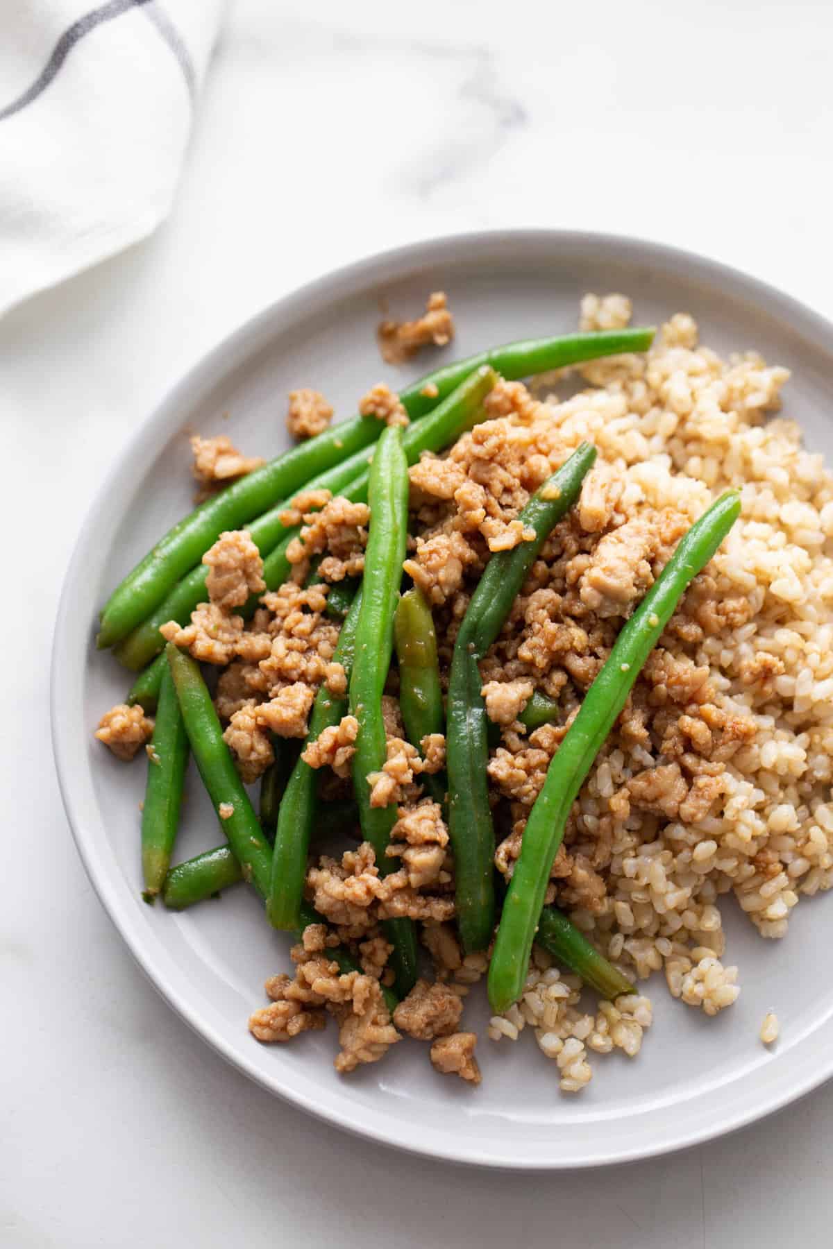 A white background and white plate with a quick ground chicken stir fry dish.