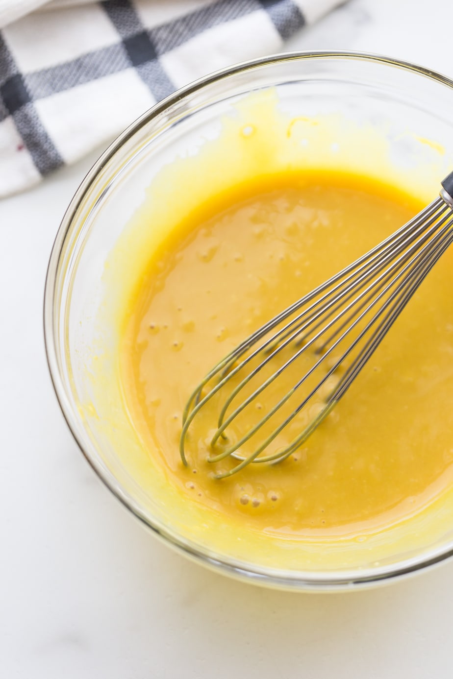 An overhead shot of a mixing bowl with a wire whisk of maple mustard sauce. 