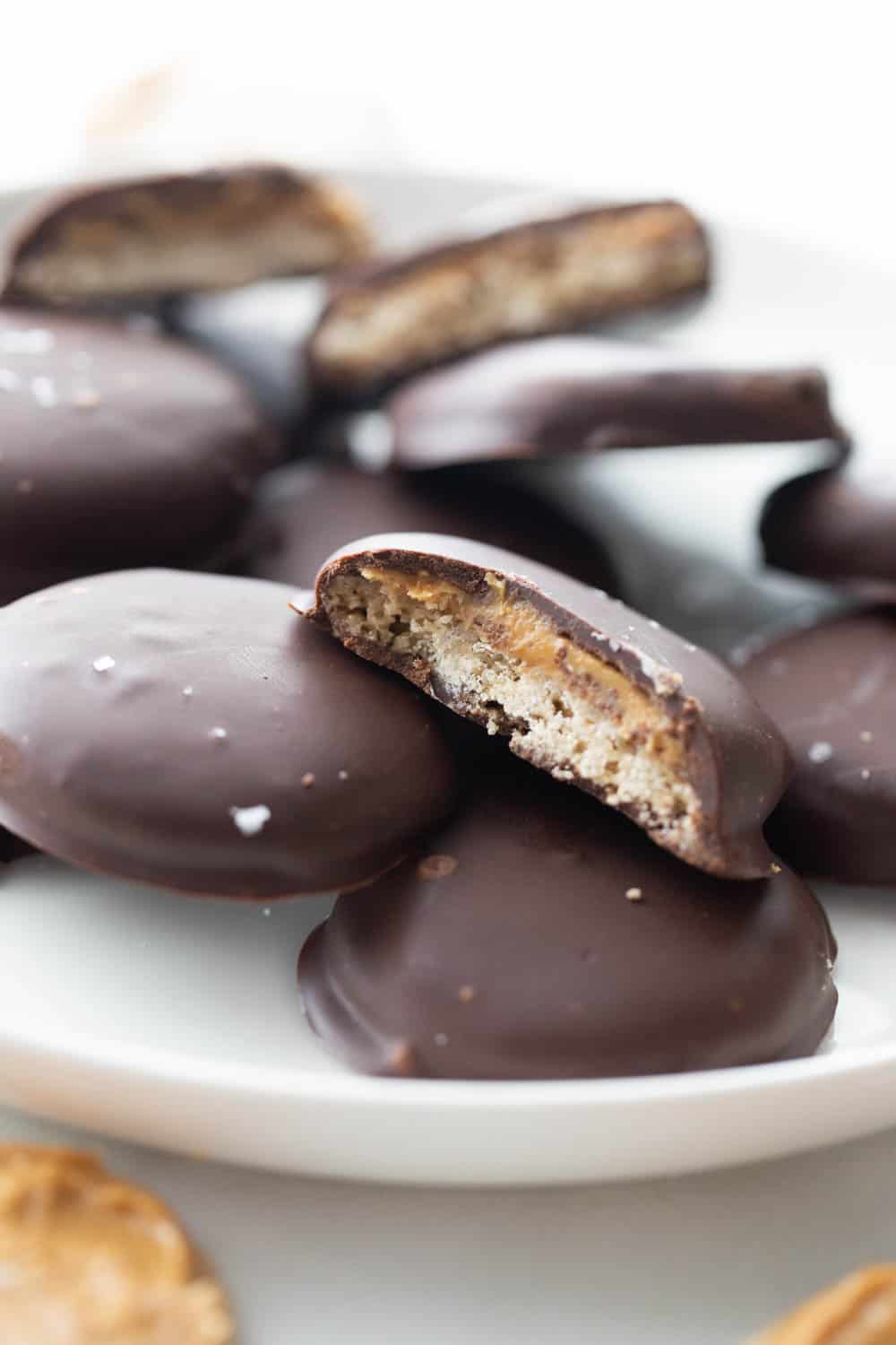 Plate of homemade tagalongs; one is bitten into exposing the cookie and peanut butter layers.