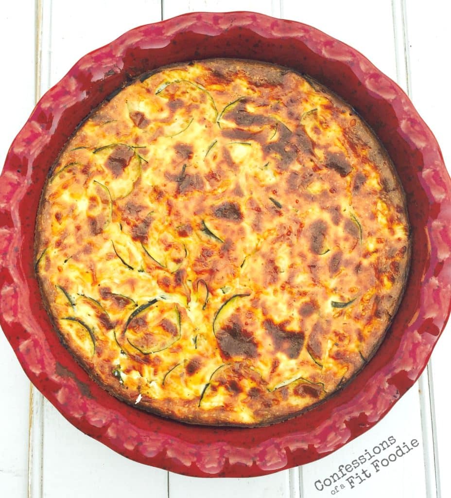 Crustless zucchini quiche in a round ceramic pie plate on a white wooden background
