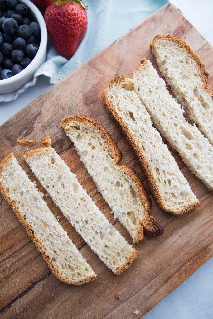 6 slices of bread for french toast sticks on a wooden cutting board