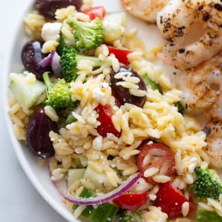 Overhead close up image of orzo salad on a white plate