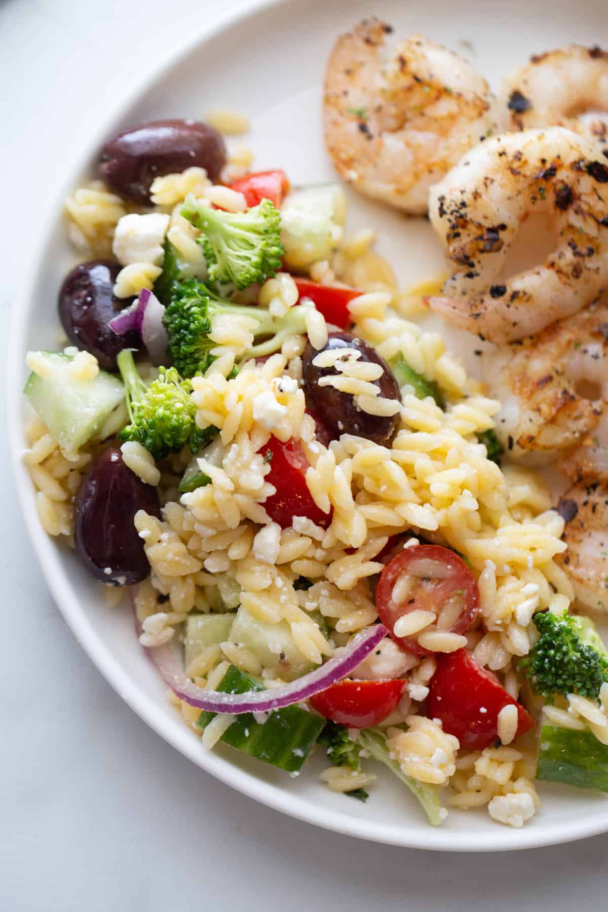 Overhead close up image of orzo salad on a white plate