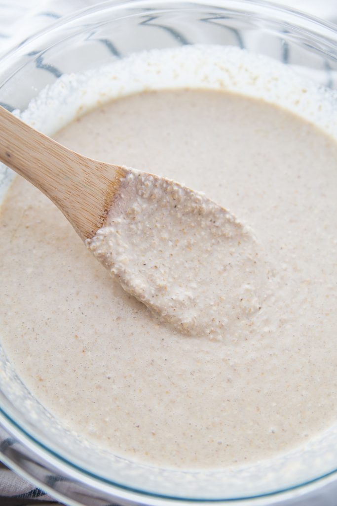 Waffle batter in a glass bowl with a wooden spoon