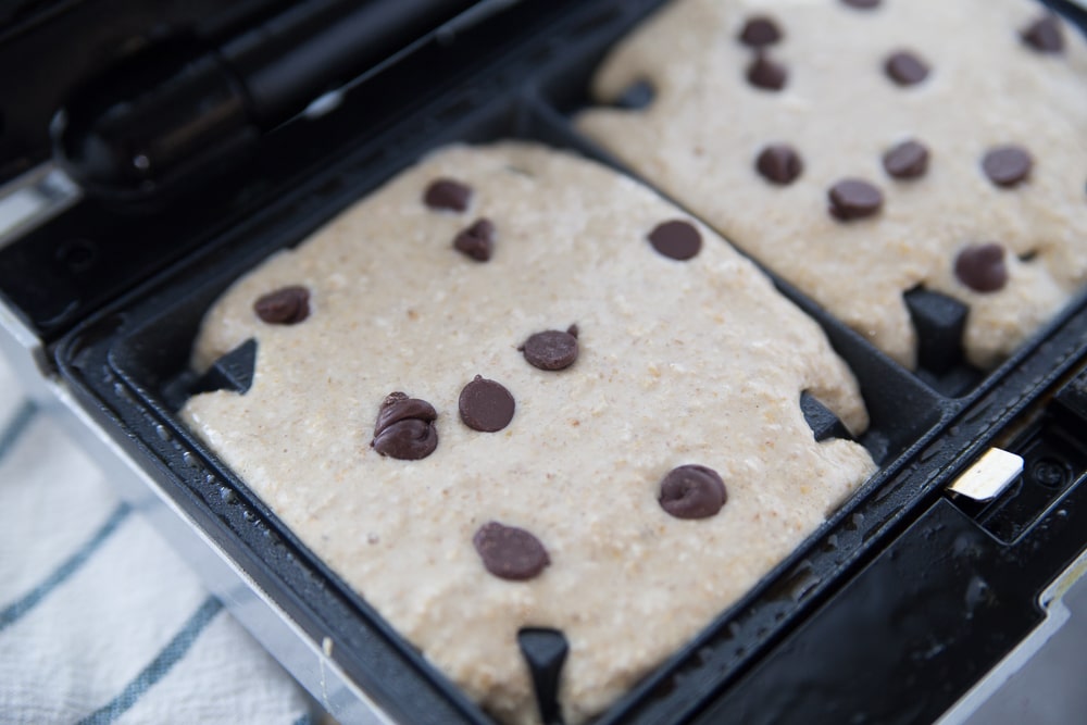 Waffle batter in a waffle maker with mini chocolate chips