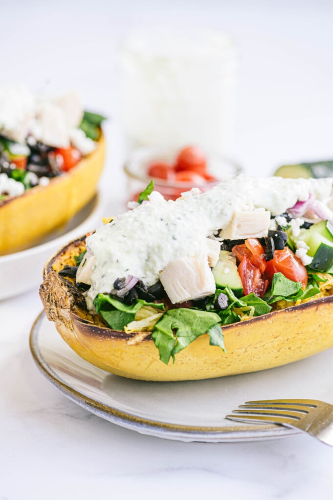 Half of a roasted spaghetti squash stuffed with chicken, veggies and homemade Tzatiki sauce