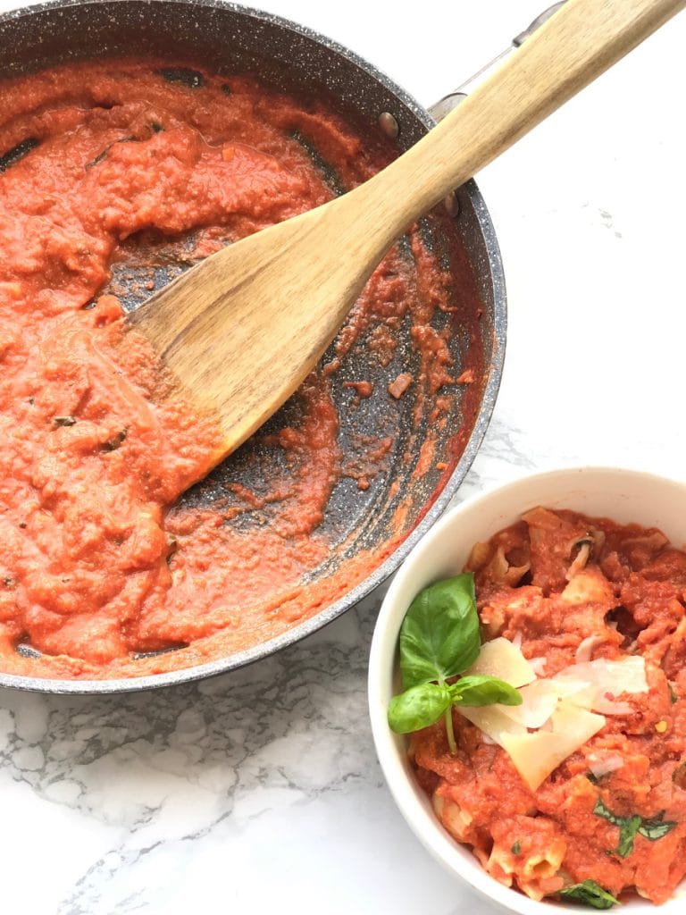 Skillet with Healthy Vodka Sauce and next to a white bowl with penne vodka and chicken 