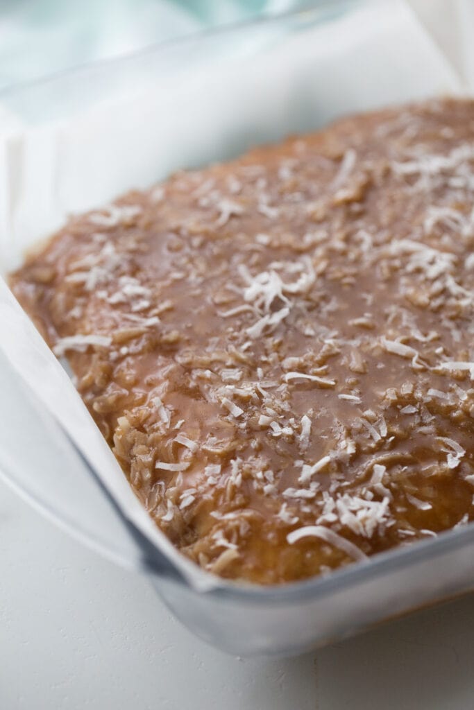 In process photo of Healthy Samoas Cookie bars- Coconut and Homemade caramel sauce smoothed out as the top layer in a glass baking dish