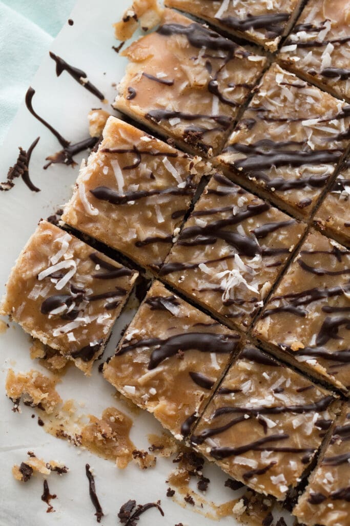 Overhead photo of a batch of Healthy Samoas Cookie Bars, cut and portioned laying on a sheet of parchment paper.