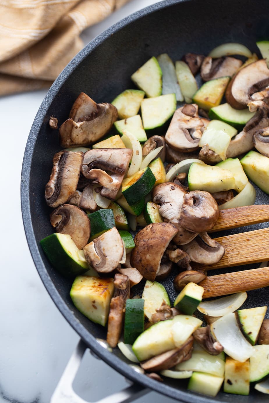 Fresh vegetables are being cooked in a skillet.