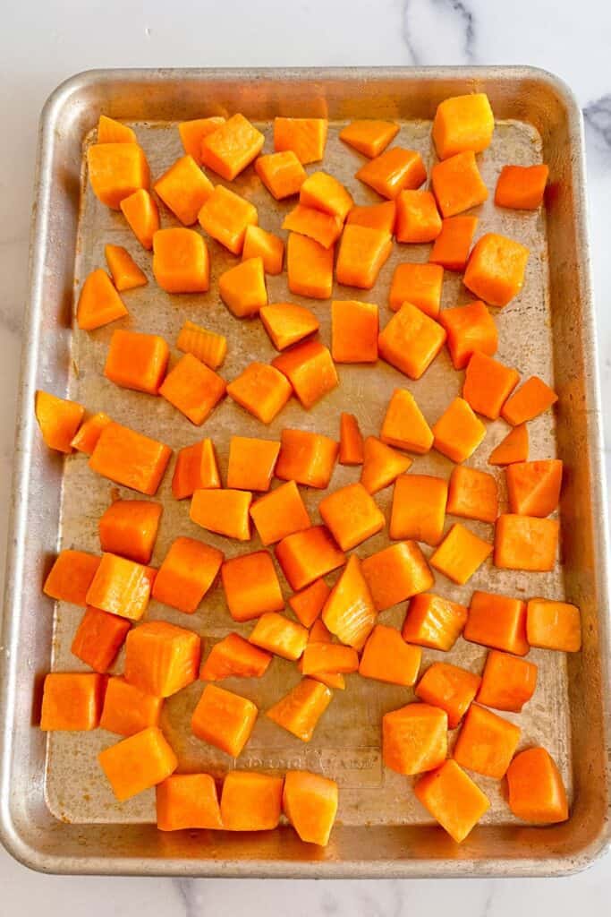 Sheet pan with diced butternut squash cubes.