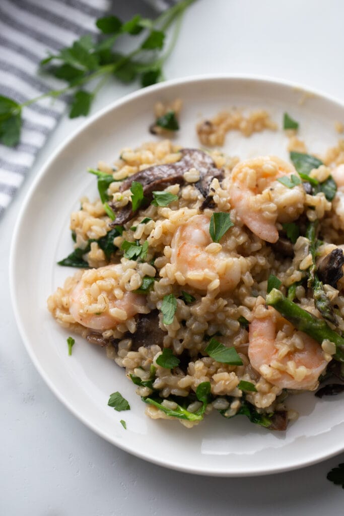 A serving of shrimp risotto is presented on a medium sized white plate.