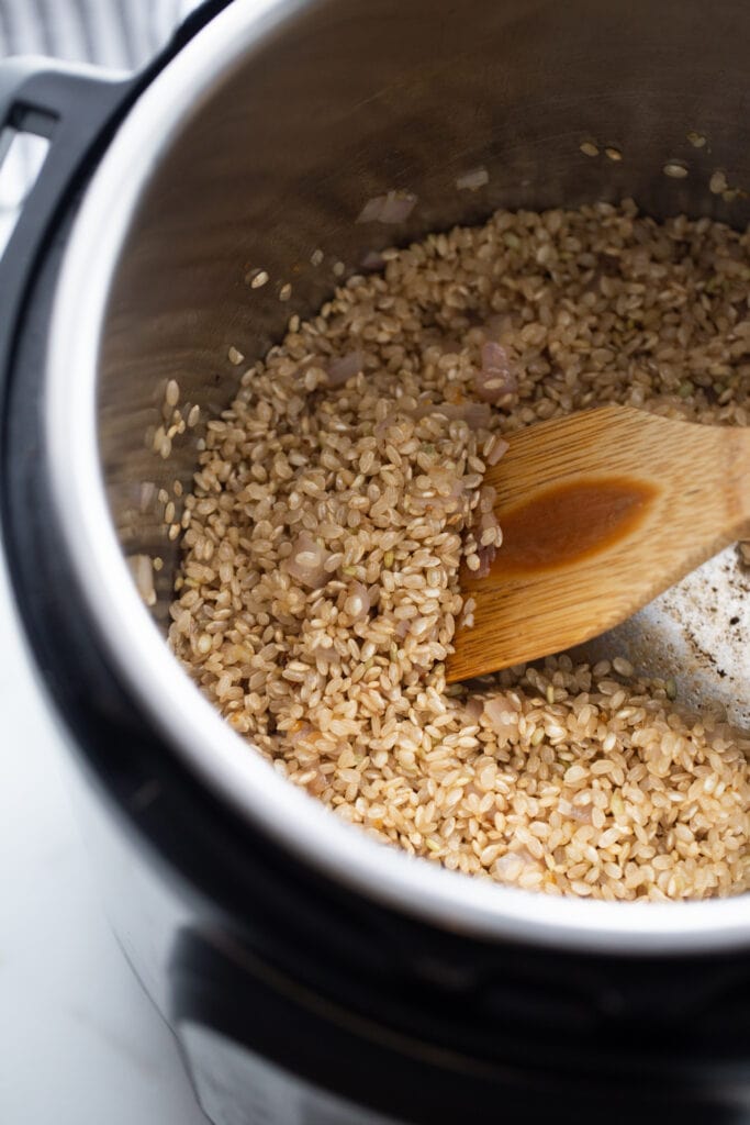 Rice is being stirred in the Instant Pot. 