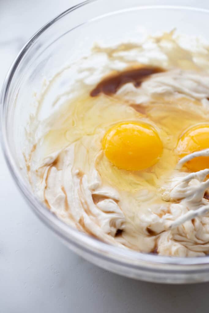 Glass bowl with wet ingredients for healthy mini cheesecakes, ready to be whipped into delicious filling.