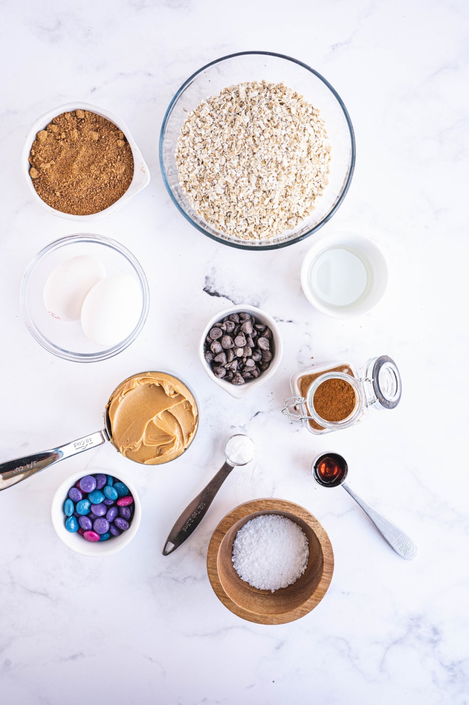 The ingredients for monster cookies are presented on a white surface.