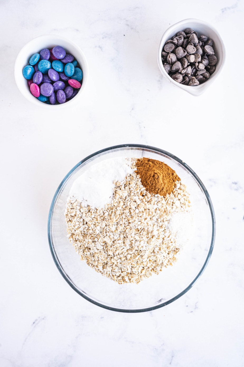 A mixing bowl has several ingredients for monster cookies. 