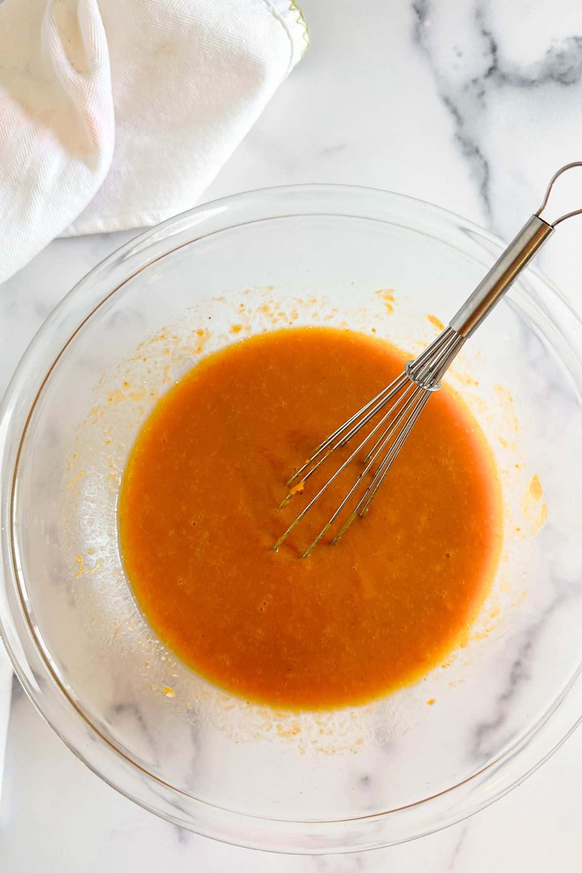 Wet ingredients for pumpkin muffins in a glass bowl.