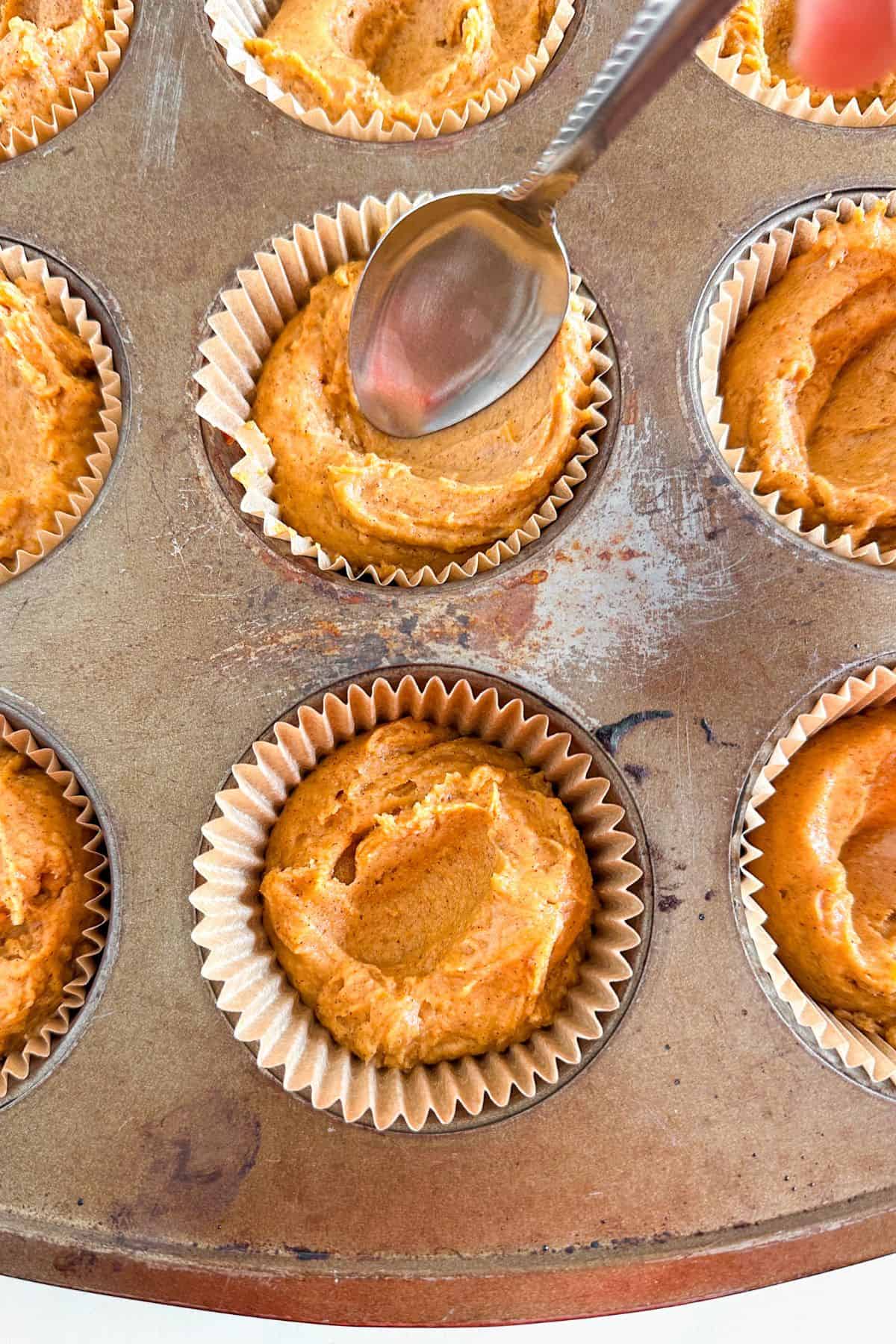 Pumpkin muffin batter in a muffin tin.