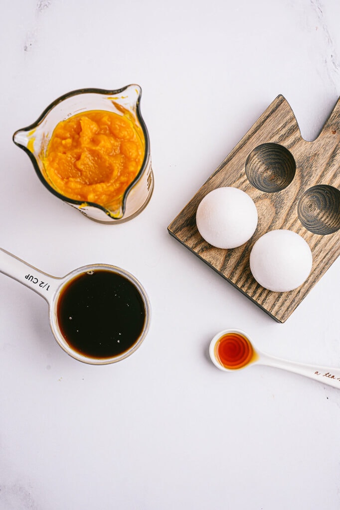 Overhead photo: individual ingredients to make pumpkin oatmeal muffins, on a white counter