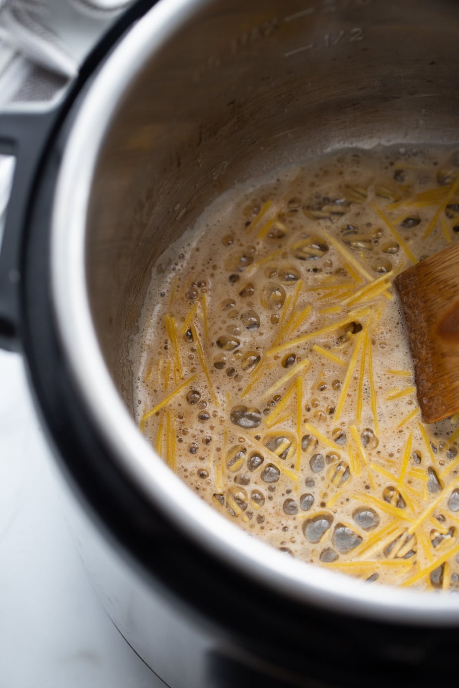 In process shot of Homemade Rice-a-Roni with broth, rice, and spaghetti in an instant pot. 