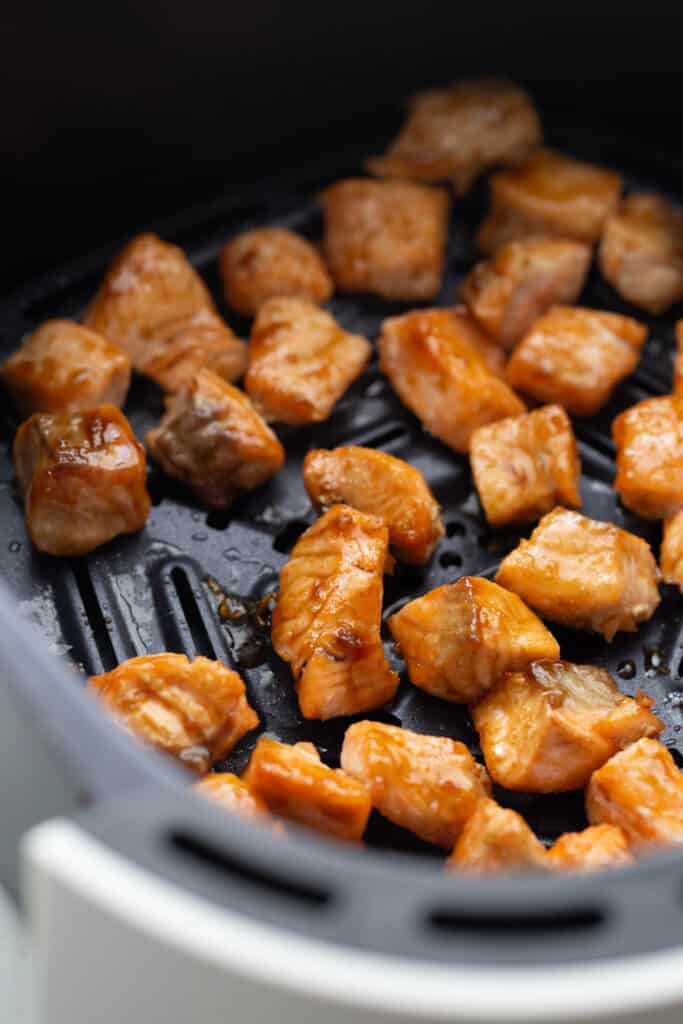 Salmon bites in an air fryer basket.