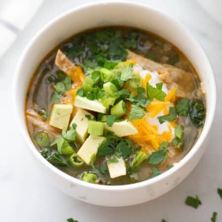 Salsa Verde Soup topped with cilantro, green onion, avocado, cheese, Greek yogurt, and homemade tortilla strips.