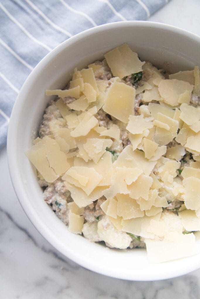 A white ceramic bowl with sausage and cauliflower casserole made with ricotta and parmesean cheese 