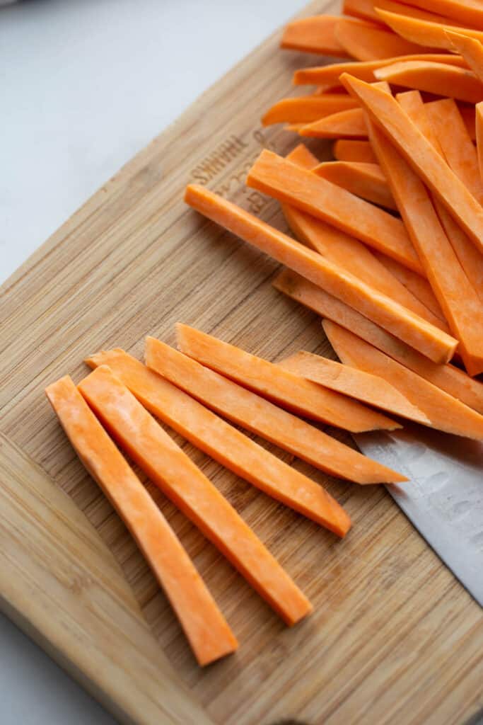 Sweet potato fries on a wooden cutting board.