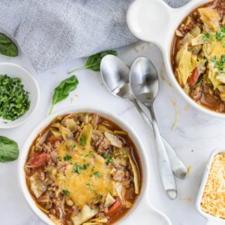 Two spoons are placed between bowls of cabbage soup.